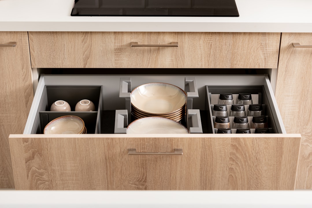 Organized kitchen drawer with plates, spices and cups in drawer organizers.