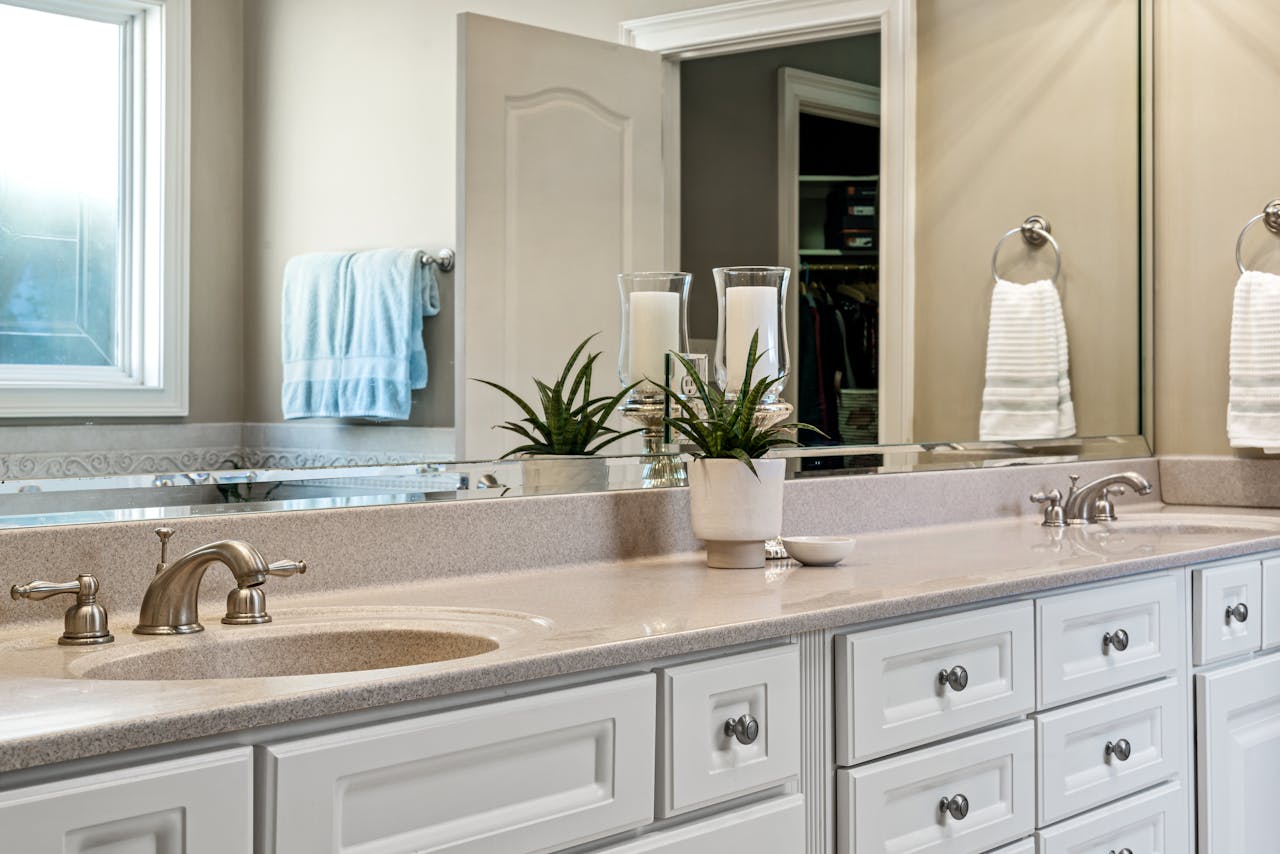 Modern bathroom featuring minimalist design with white cabinets, large mirror, and stylish faucets.